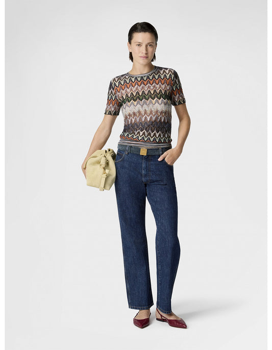 Woman wearing Missoni patterned sweater and blue jeans holding a beige jacket